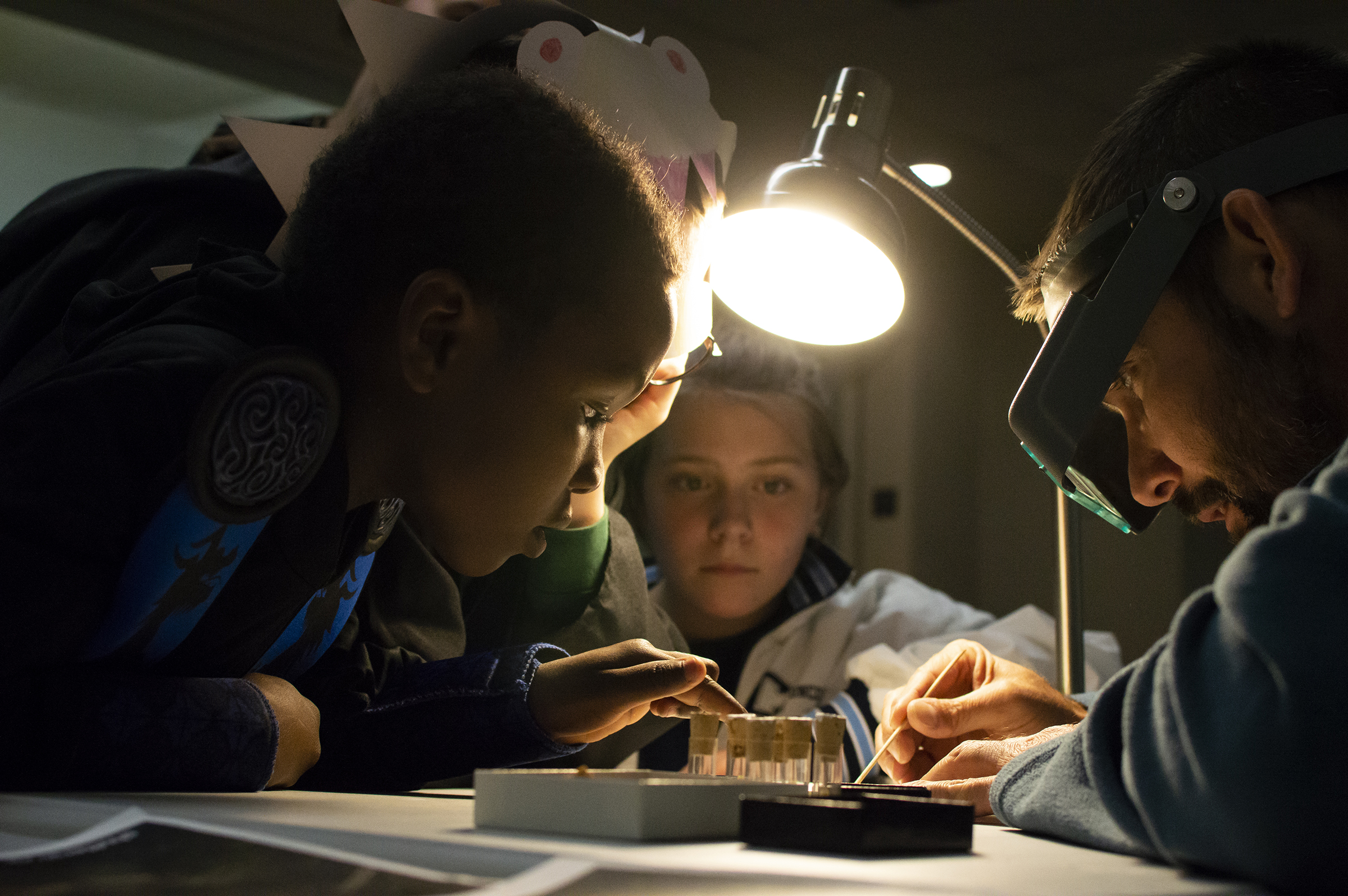 Shane Tucker (right), highway paleontologist with the University of Nebraska State Museum, shows visitors how microfossils are sorted during a previous Fossil Night event.