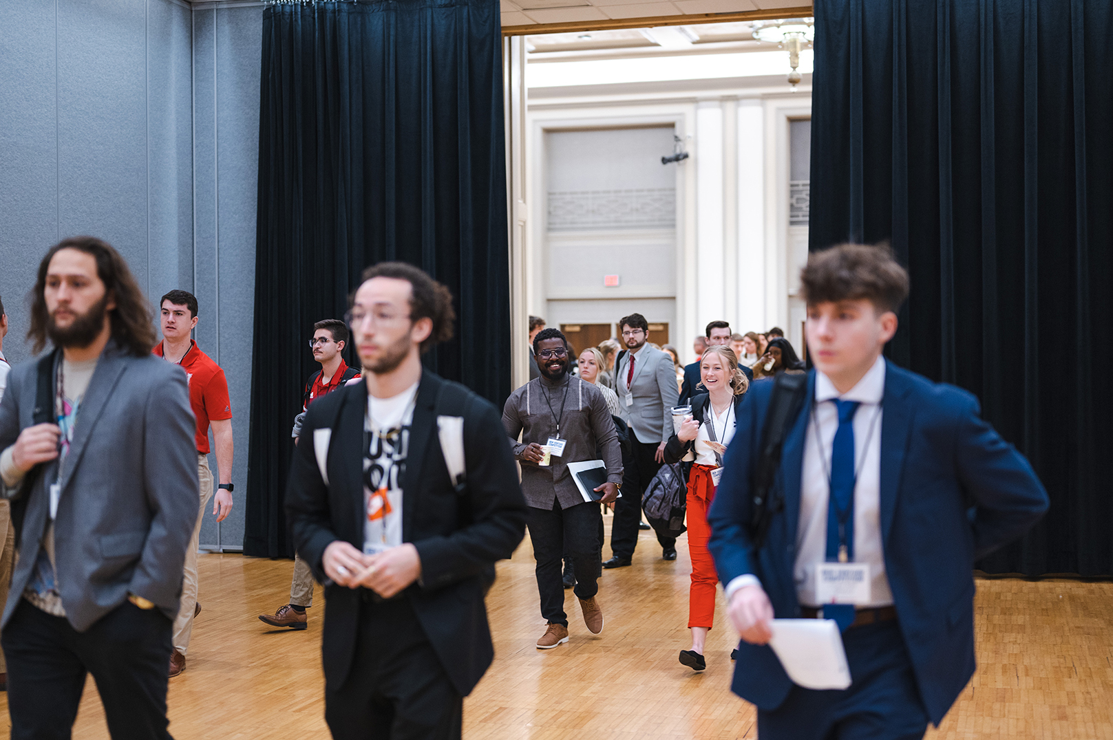 Participants in the 2023 New Venture Competition walk in a large ballroom.