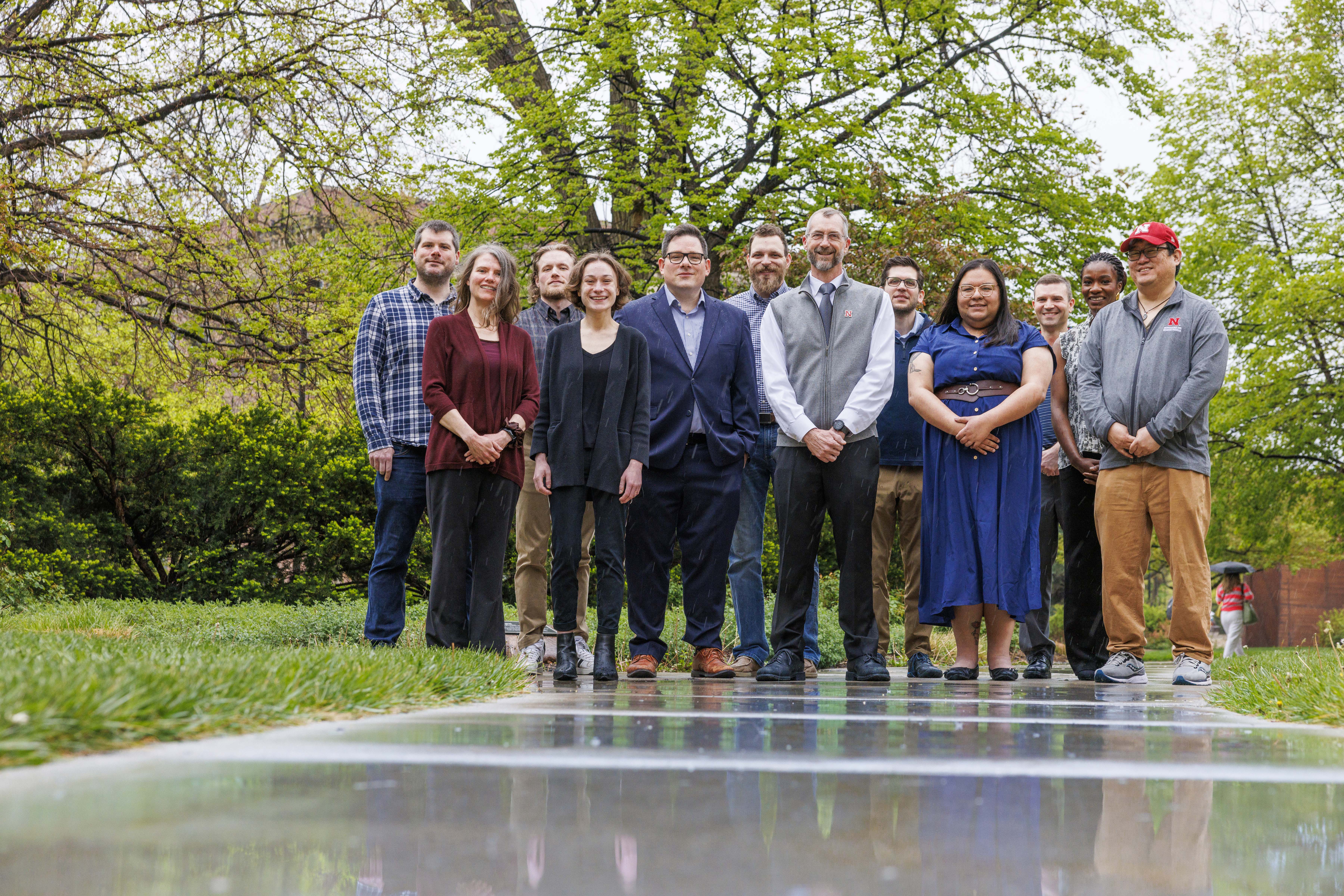 Twelve people stand on a sidewalk and lawn.