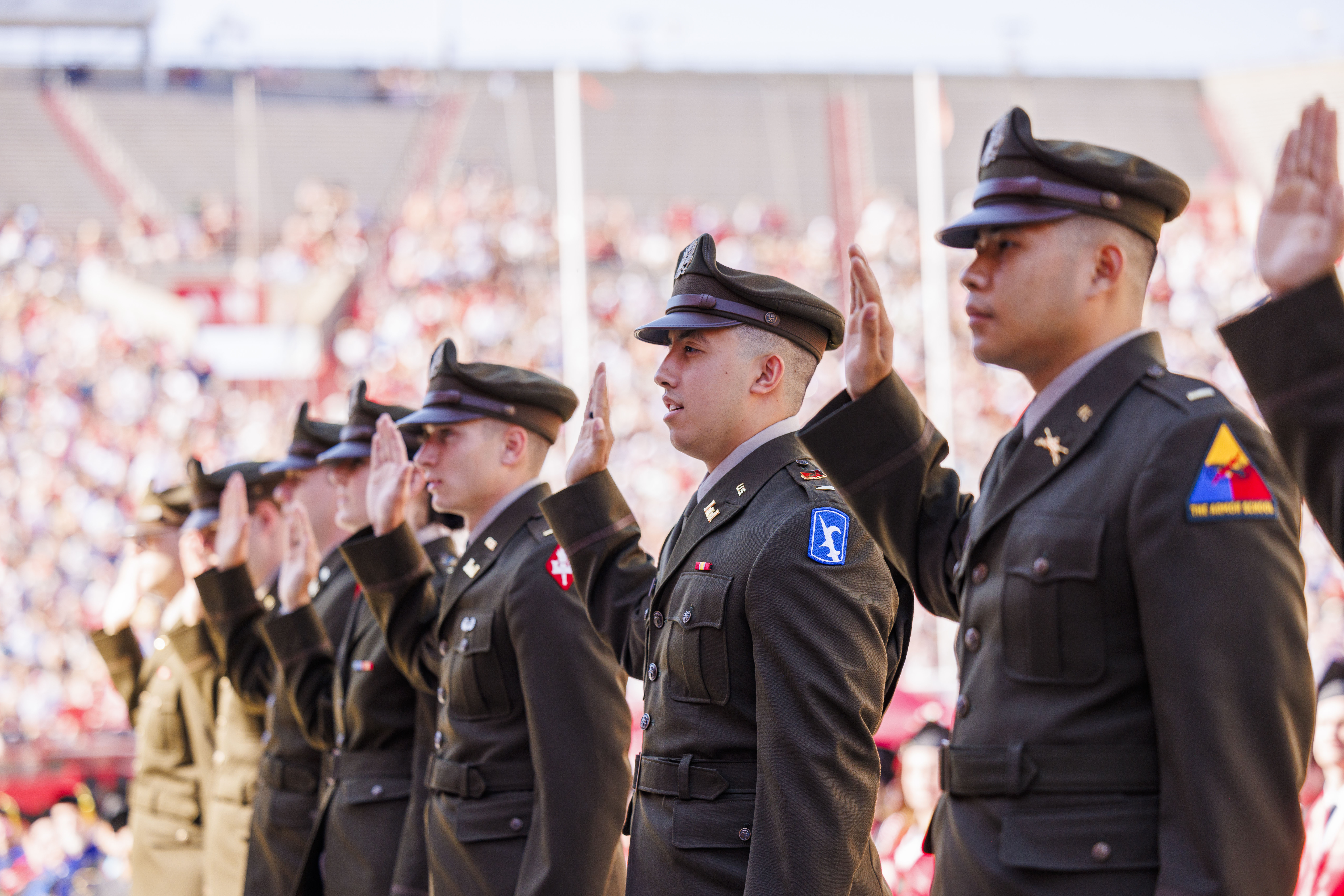 Air Force, Army and Naval ROTC members hold up their right hands as they recite the oath of enlistment at Memorial Stadium.