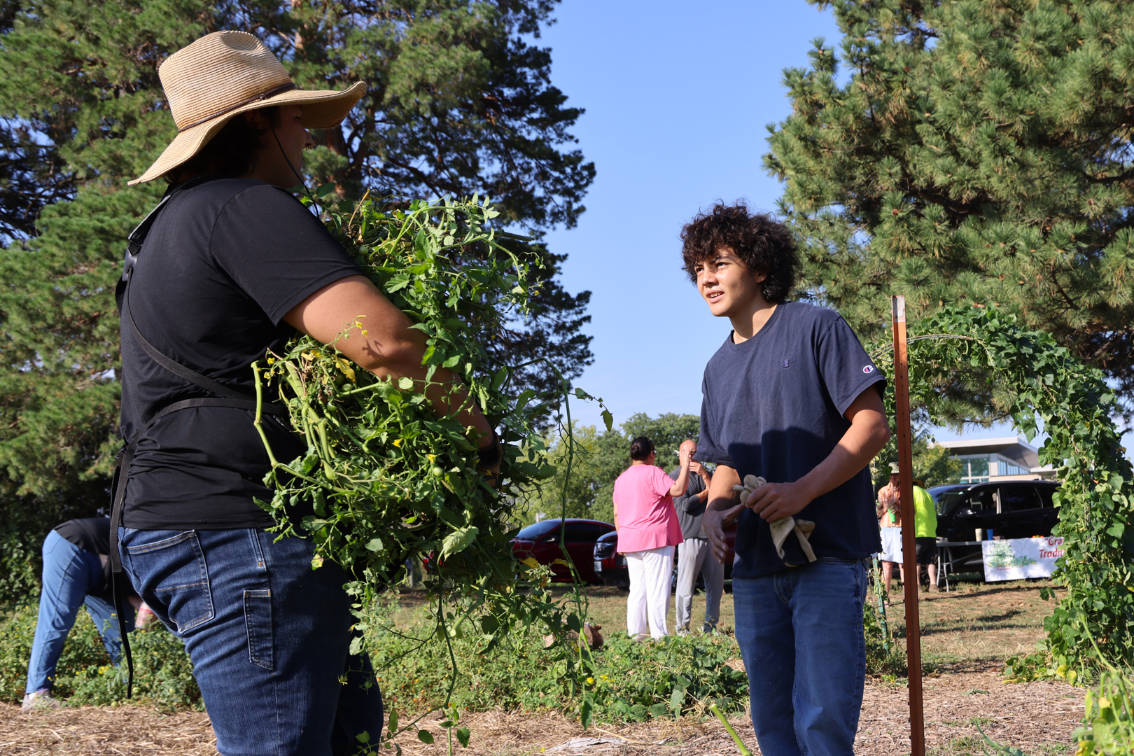 Timothy Thielen, arms full of plants, talks with a youth.