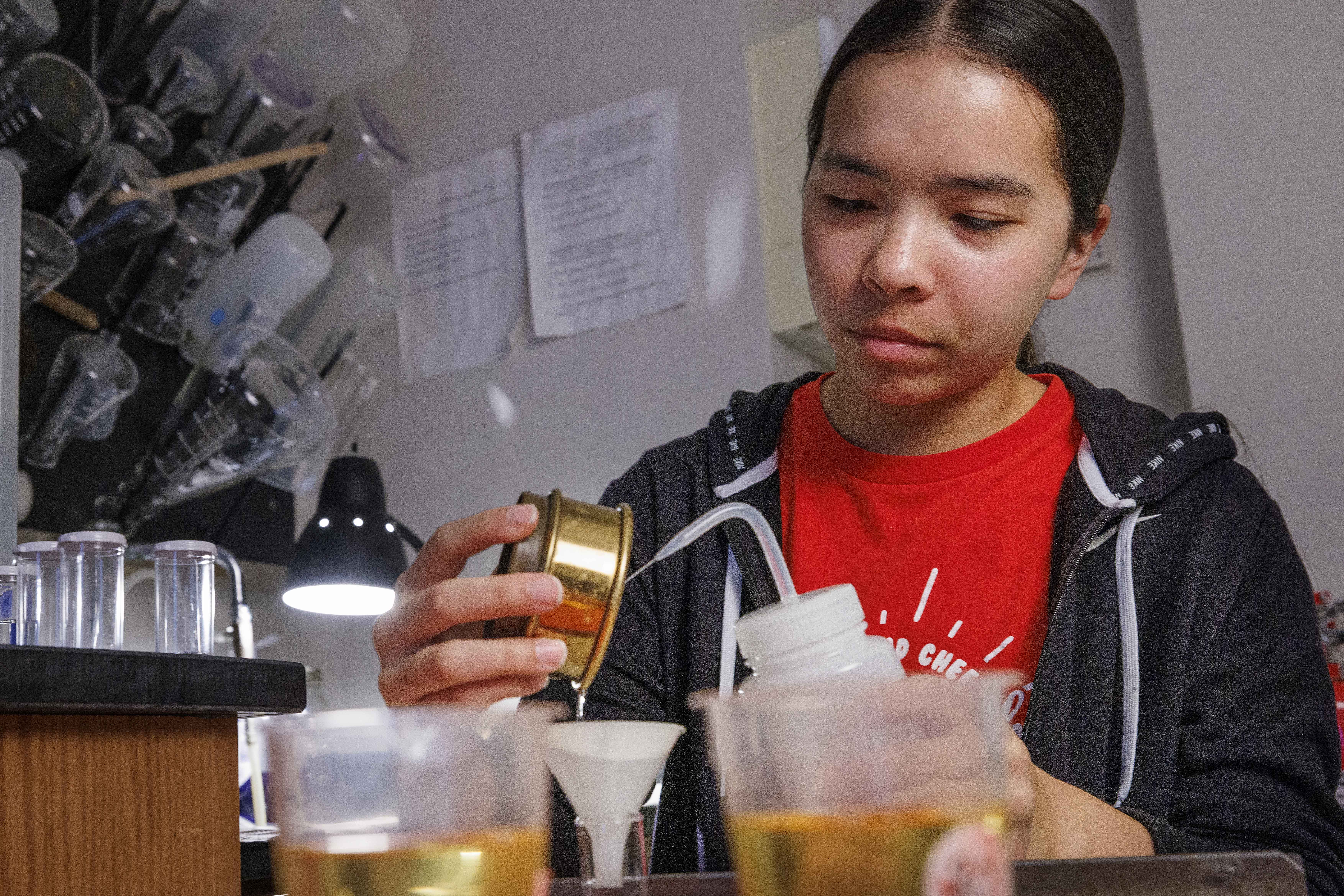 UCARE student Jasmine Pham washes a sieved soil sample into a container for analysis.