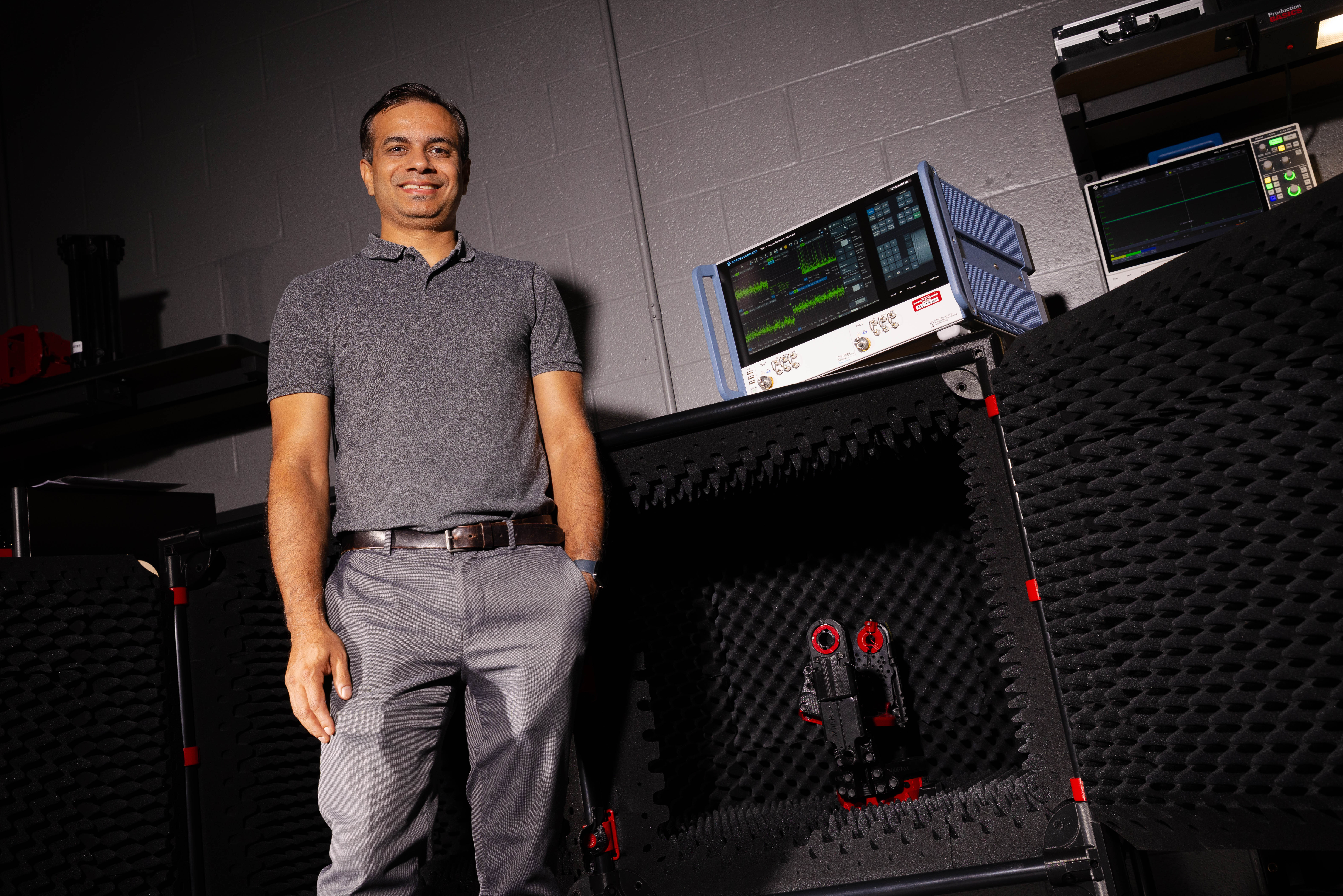 Shubhendu Bhardwaj, associate professor of electrical and computer engineering, poses in a lab in front of a compact chamber lined with foam.