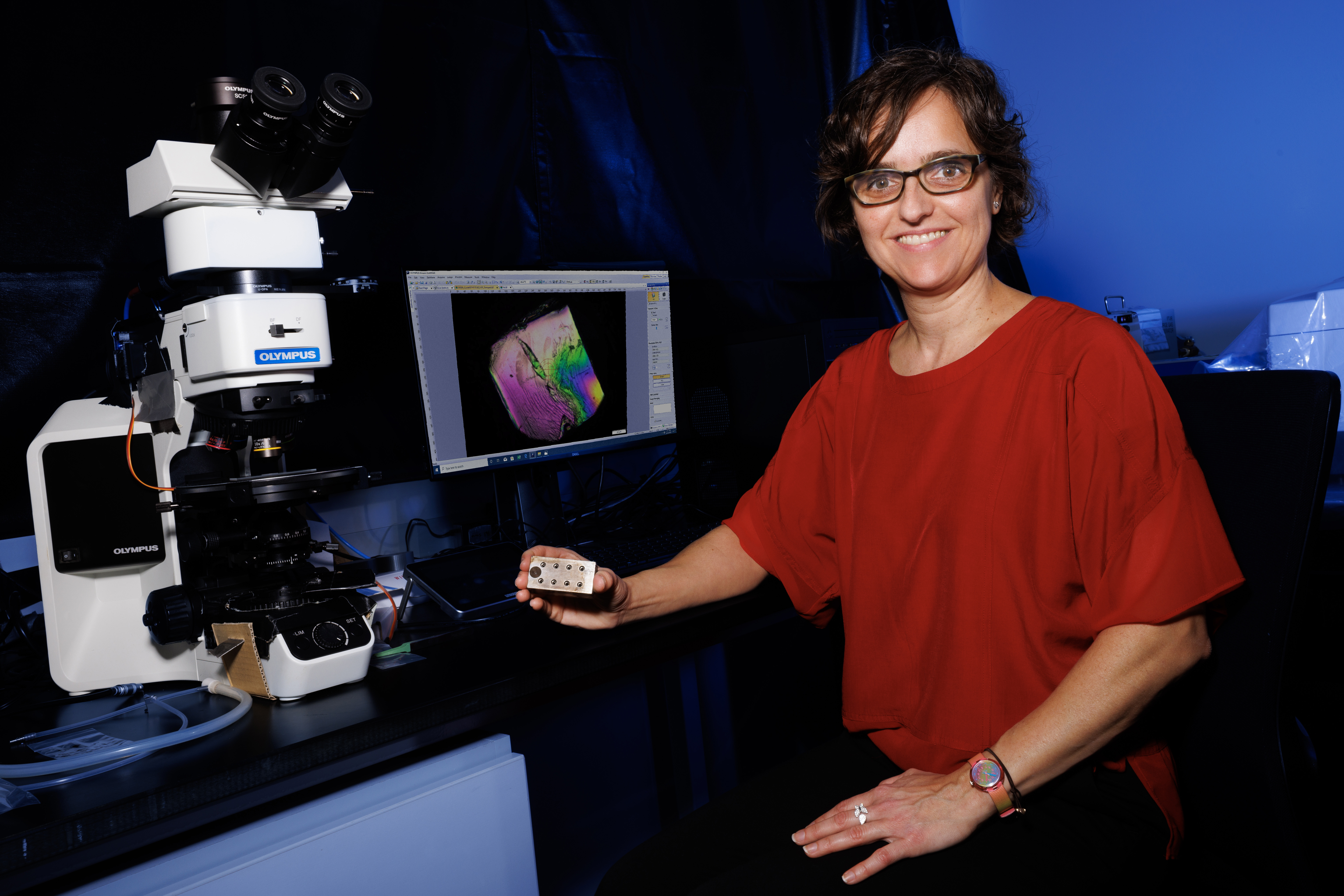 Lucia Fernandez-Ballester, assistant professor of mechanical and materials engineering, poses next to a microscope and computer monitor in a lab.