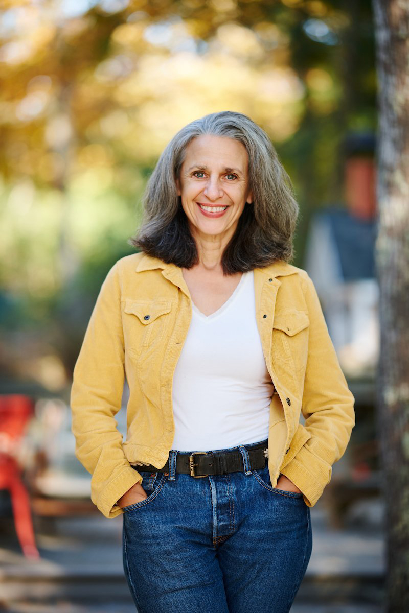 Color portrait of Tamar Haspel, food columnist for The Washington Post, posing outdoors in a yellow jacket, white V-neck and blue jeans.