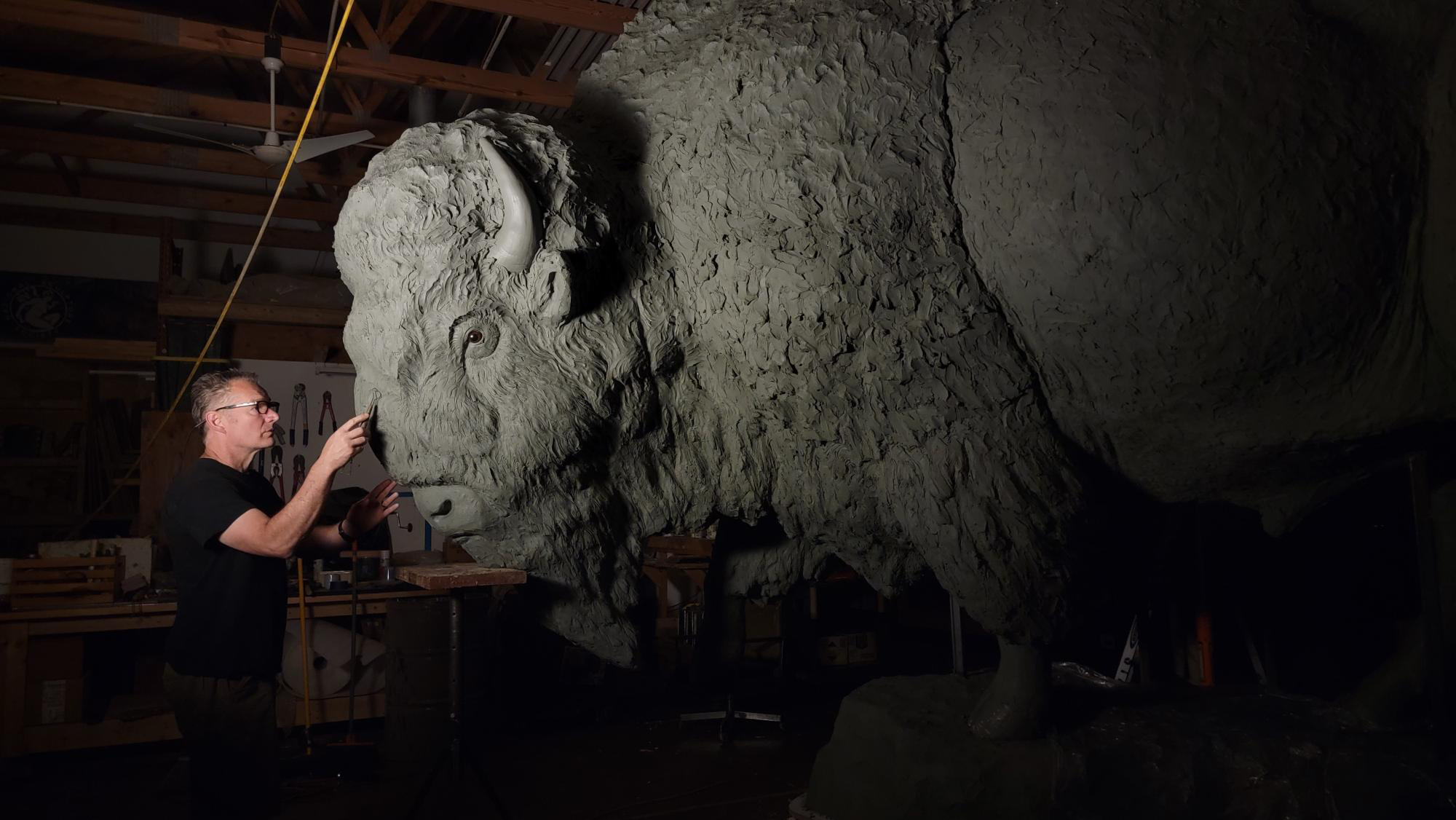 Nebraska artist Gary Staab carves the face of one of the bison statues.
