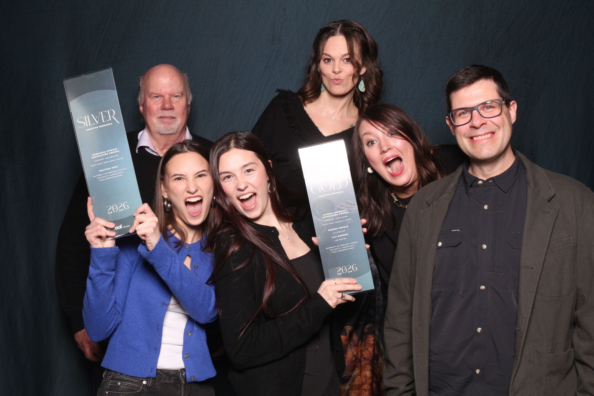 Four women and two men pose with two awards.