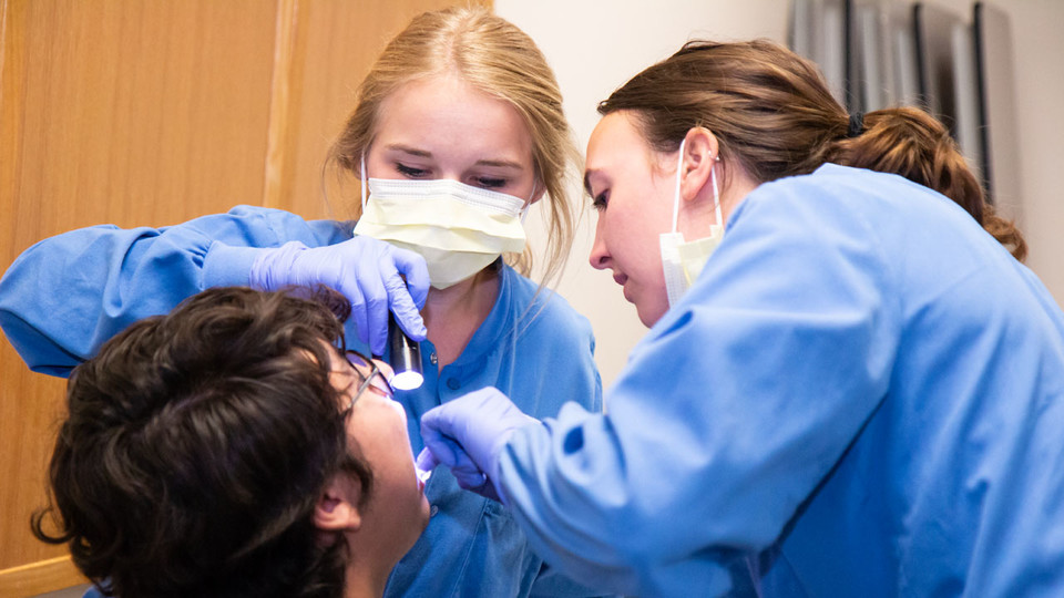 Patient Oscar Kaled Gonzales gets a checkup from Nebraska College of Dentistry students Maddi McConnaughhay and Olivia Straka at Lincoln's El Centro de las Américas. (Photo by Kyleigh Skaggs, CYFS)