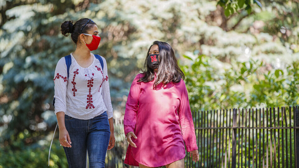 Asmita Jayswal, a junior in computer science (right), and Esha Mishra, a graduate student in physics, walk along R Street wearing the new N face mask. More than 60,000 face masks will be distributed to all students, faculty and staff for fall semester.