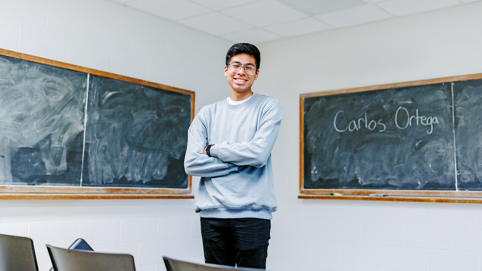 Carlos Ortega smiles for a photo in a classroom on campus