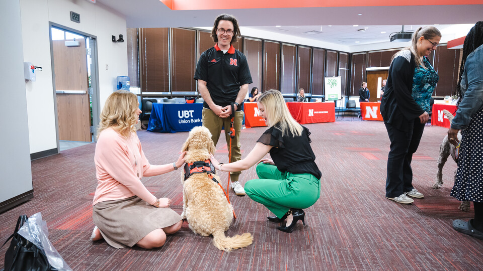 Photo Credit: Garrett Stolz // Brett Neely smiles for a photo as Marko receives some attention from Huskers during a Pawp Up event on campus.