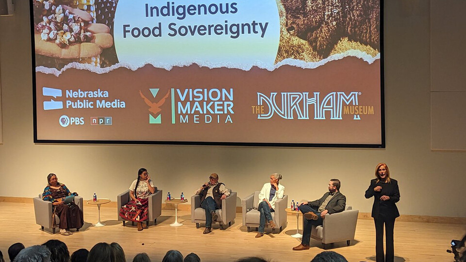 A panel of Indigenous conservationists, activists and artists sit while talking from a stage