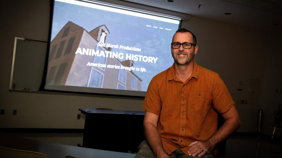 Michael Burton sits in front a projection that reads "Animating History"