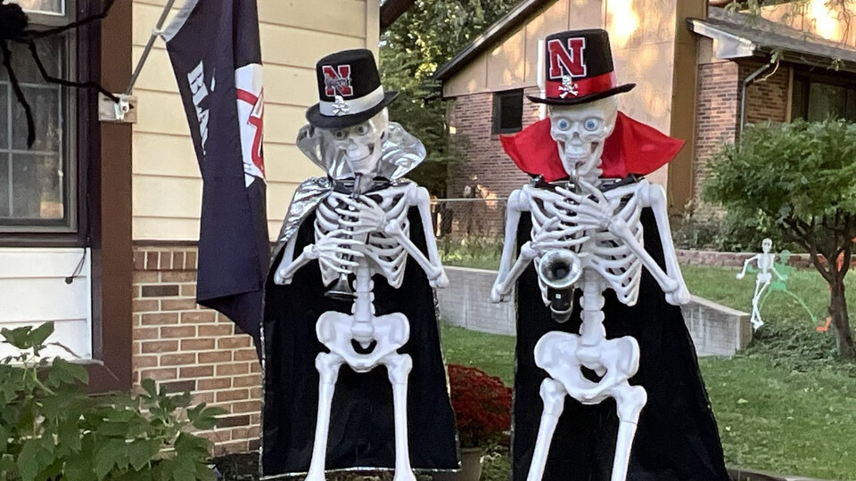 Two skeletons play musical instruments while wearing Husker-branded hats