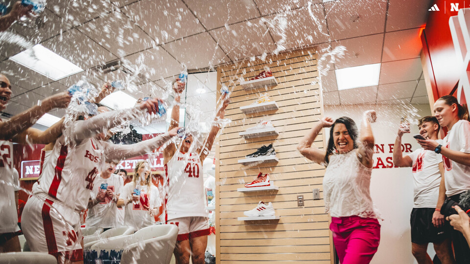 The women’s basketball team showers head coach Amy Williams with water during a celebration in the locker room