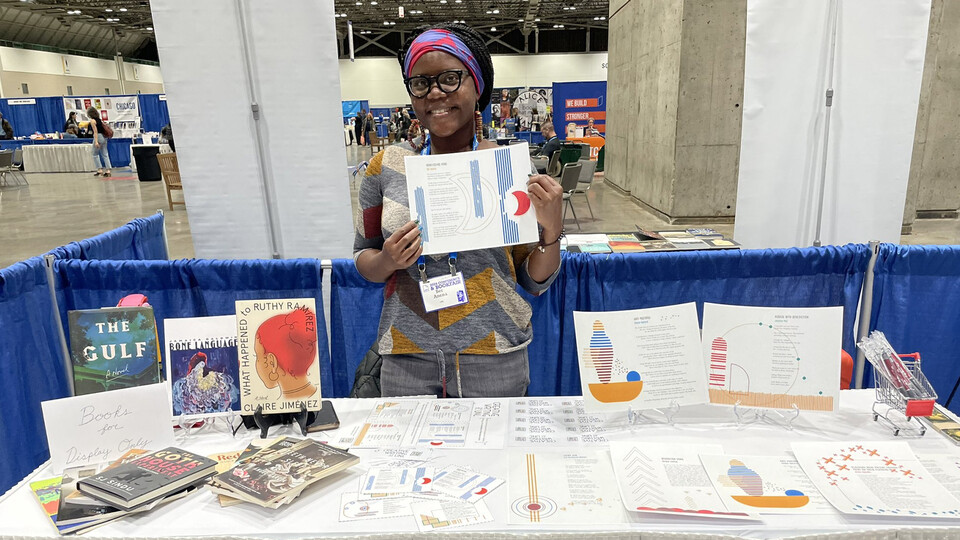 A member of the Creative Writing Program holds up a poem at a conference booth