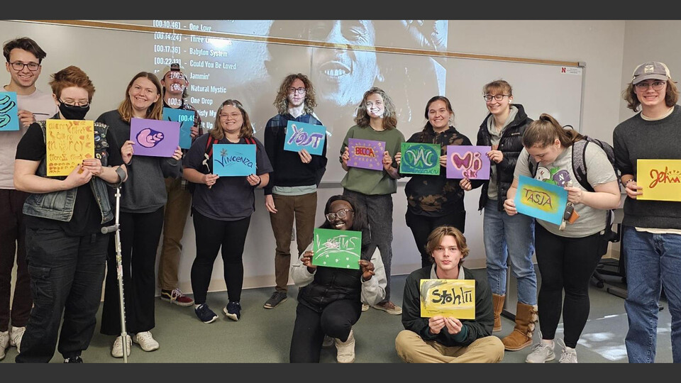 Students in HIST 286 hold up album cover concepts for a protest song