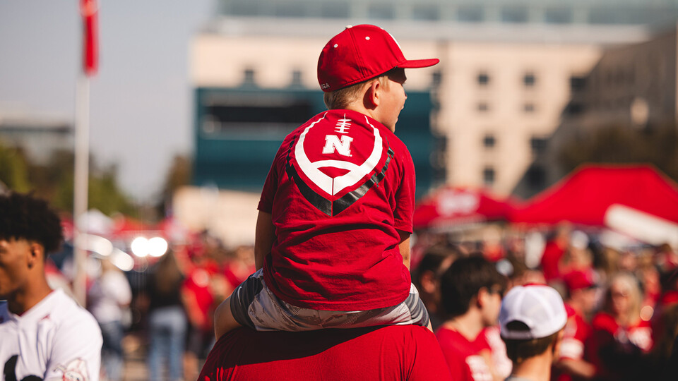 A young Husker fan sits atop the shoulders of a parent on game day