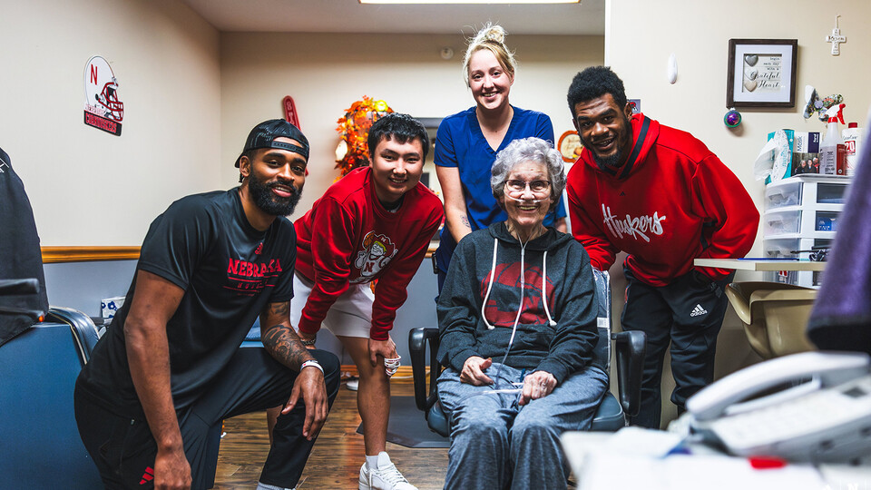Husker basketball players posing with fan at retirement community