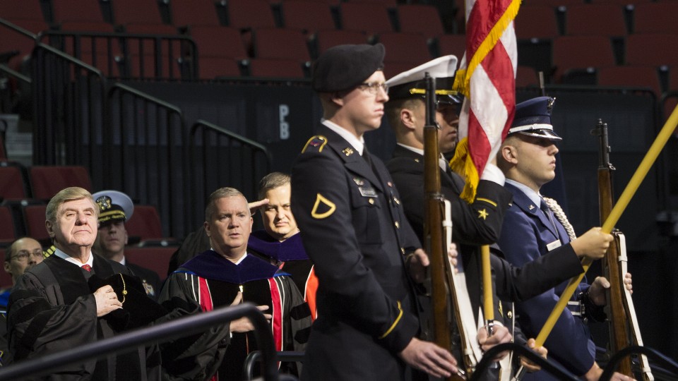 Former Sen. Ben Nelson (left) and the rest of the platform party salute the flag during commencement activities in December 2013. Starting with UNL commencement exercises in December, graduating military veterans and students receiving ROTC commissions can wear a special military cord on their graduation regalia.