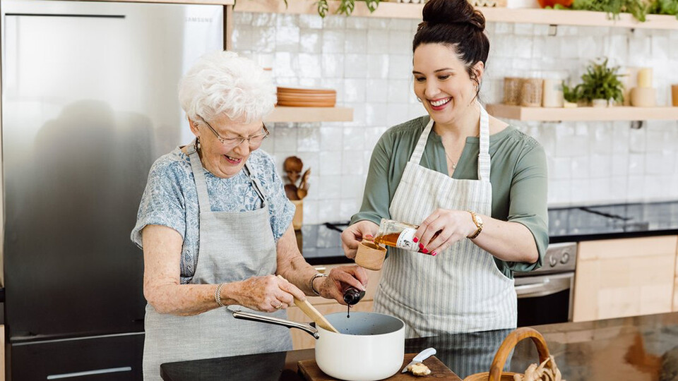 Tessa Porter and her grandmother, Norma, add ingredients to a pot while preparing to bake treats