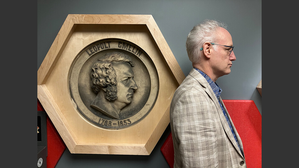 Mark Griep, professor of chemistry, poses next to a plaster medallion of Leopold Gmelin, a German scientist. The medallion is one of two on display on the fourth floor of Hamilton Hall. They once decorated Chemical Laboratory, the Department of Chemistry’s first home. Learn more at https://go.unl.edu/p4y5.