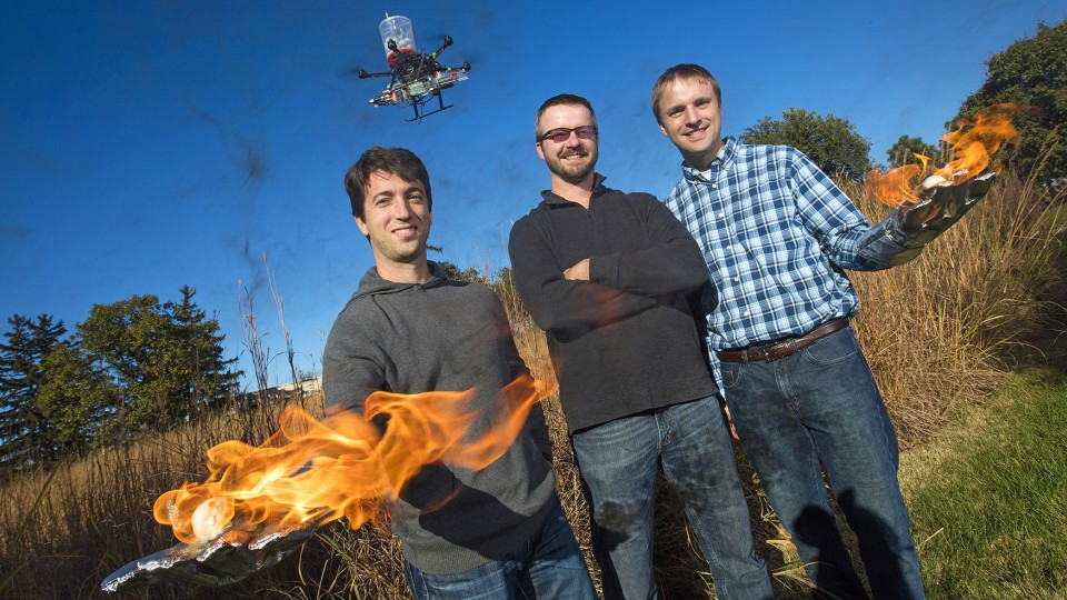 Sebastian Elbaum (from left), Dirac Twidwell and Carrick Detweiler have developed a patent for setting range fires with small drones. The drone injects a liquid into plastic spheres to start a delayed fiery process that allows the balls to fall to the ground before igniting. Elbaum and Detweiler are holding flaming tennis balls similar to those carried by the drones.
