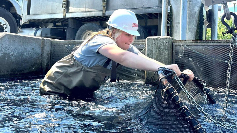 Jayla Dagen wearing a hard hat and wader while working in waist-deep water