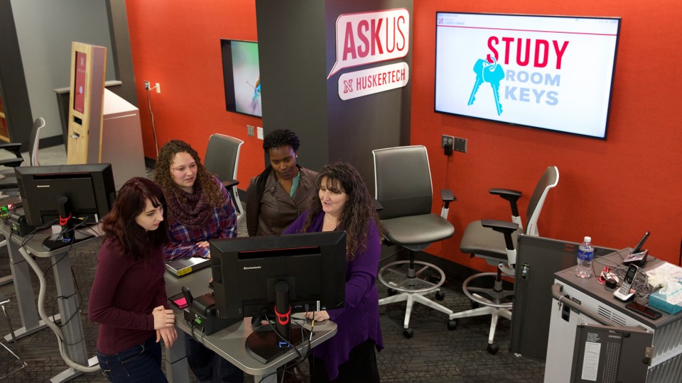 (From right) Julie Kirk shows student workers Darleen Ademba, Stacie Bub and Chelsea Lemburg how to use the resources offered at the service desk within UNL’s new Learning Commons at Love Library. The Learning Commons will assist with regular library services and information technology issues.
