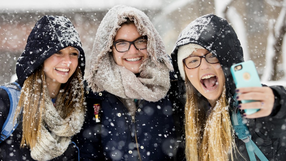 Kayla Felix (from left) and Alli Hauger smile as Emily Hames takes a selfie while they walked to class as snow fell on Jan. 25. 