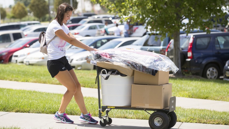 Amy Prusa of Omaha backs her belongings up the sidewalk at UNL's Harper-Schramm-Smith residence hall complex. Move in to UNL residence halls continues through the week as classes begin Aug. 22.