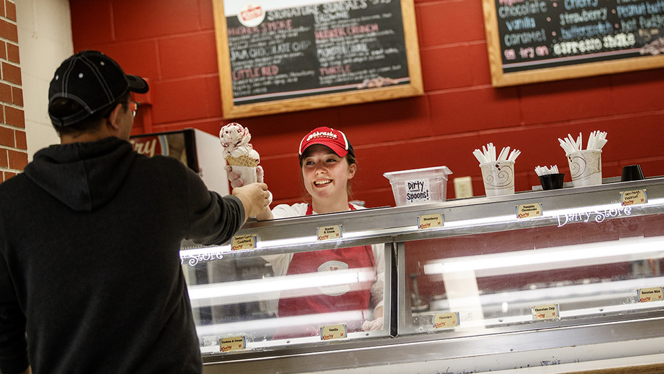 A Dairy Store employee serves a cone filled with Scarlet and Cream ice cream. The flavor is among the top five most popular served at the iconic campus store.