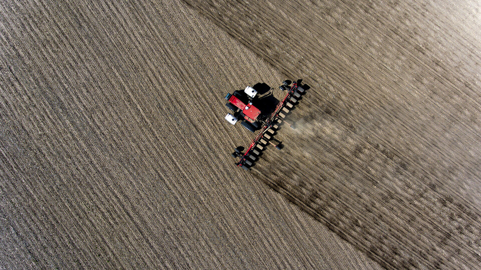 Aerial shot of a red combine rolling across a field during harvest.