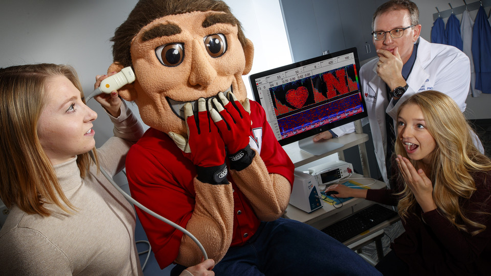 Biological systems engineering students and faculty examine Herbie Husker's love for Nebraska using a transcranial Doppler ultrasound, which measures real-time blood flow through the cerebrovascular system. The technology is used to detect changes in blood flow patterns as indicators for traumatic brain injury, stroke and Alzheimer's disease.