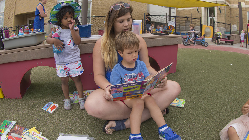 Emily Byers, a sophomore pre-elementary education and special education major, reads to a student during playground time at the Children's Center on June 4. 