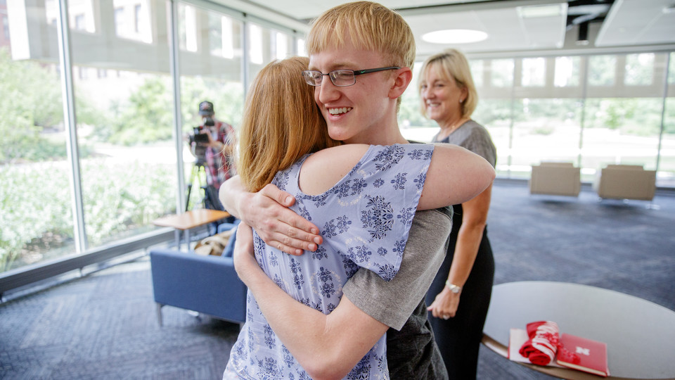 Samuel Harvey is hugged by his mother, Elisia Flaherty, after being presented a scholarship by Donde Plowman