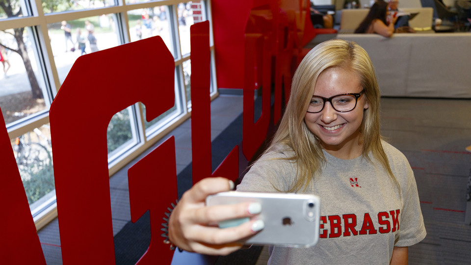 Husker Alyssa Frederick takes a photo next to the "Glory" sign in the Nebraska Union. The "Grit" and "Glory" signs, along with related sidewalk art and a website, appeared the week of Aug. 20.
