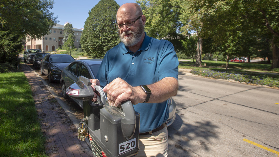 Bill Manning checks a malfunctioning parking meter on East Campus. Manning, who has worked for 40 years at the university, is among the 960 faculty and staff who will receive honors for years of service on Sept. 25.
