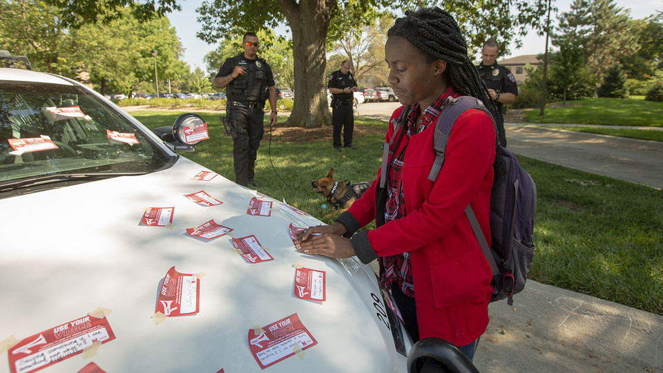Elizabeth Uwase, a junior integrated science major from Rwanda, affixes her "Use Your Voice" pledge to a police car during the Sept 10 Cover the Cruiser event on East Campus. More than 75 students, faculty and staff made a pledge to stand up to sexual violence in the first day of the initiative.