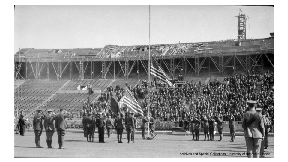 The American flag is raised to half-staff as soldiers salute during the 1923 dedication of Memorial Stadium