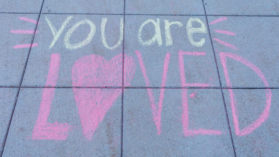 Sidewalk-chalk message reading "You are loved"