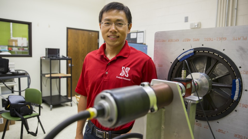 Jie Cheng, doctoral student in electrical engineering, stands next to the partial prototype of a wind turbine system that research suggests could yield 8.5 percent more electricity than conventional counterparts.