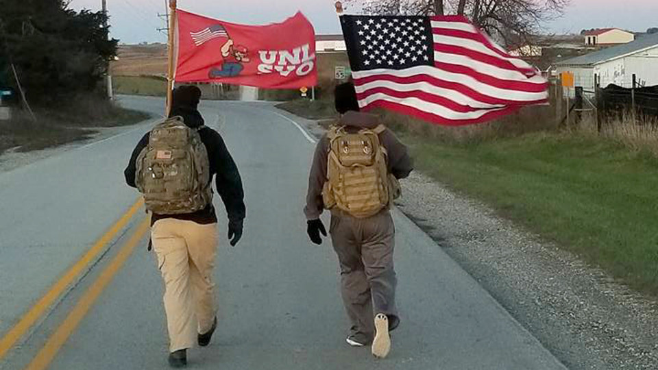 Members of the Nebraska Student Veteran Organization walk along an Iowa highway during the 2017 The Things They Carry Ruck March. The event, organized by Nebraska and Iowa students, is designed to raise public awareness of veteran suicides.