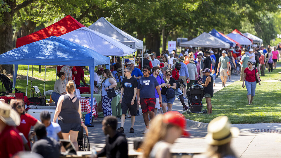 A crowd of people walks by vendor tents during an East Campus Discovery Days farmers market in Lincoln in summer 2021.
