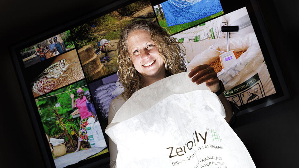 Georgina Bingham holds a ZeroFly bag in a dark room with photos in the background