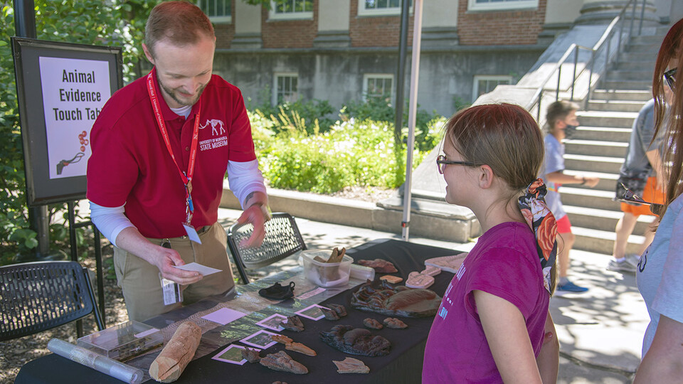 A young visitor chats with Adam Eakin, assistant director of the NU State Museum, at an animal traces identification activity station during the 2021 Archie’s Party.