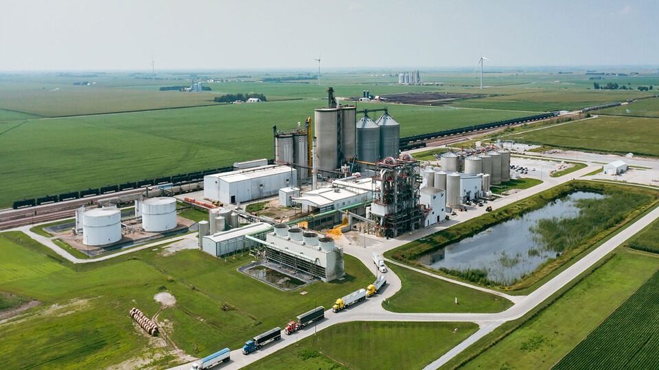 Aerial photo of bioprocessing facility, surrounded by farm fields, with line of semitrucks exiting