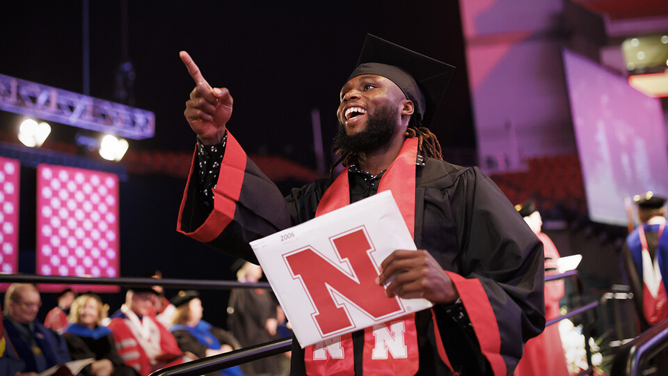 Papay Glaywulu, dressed in graduation attire, points to family and friends after receiving his degree during the combined graduate and undergraduate commencement ceremony Aug. 13 at Pinnacle Bank Arena. He earned a Bachelor of Science in Education and Human Sciences.