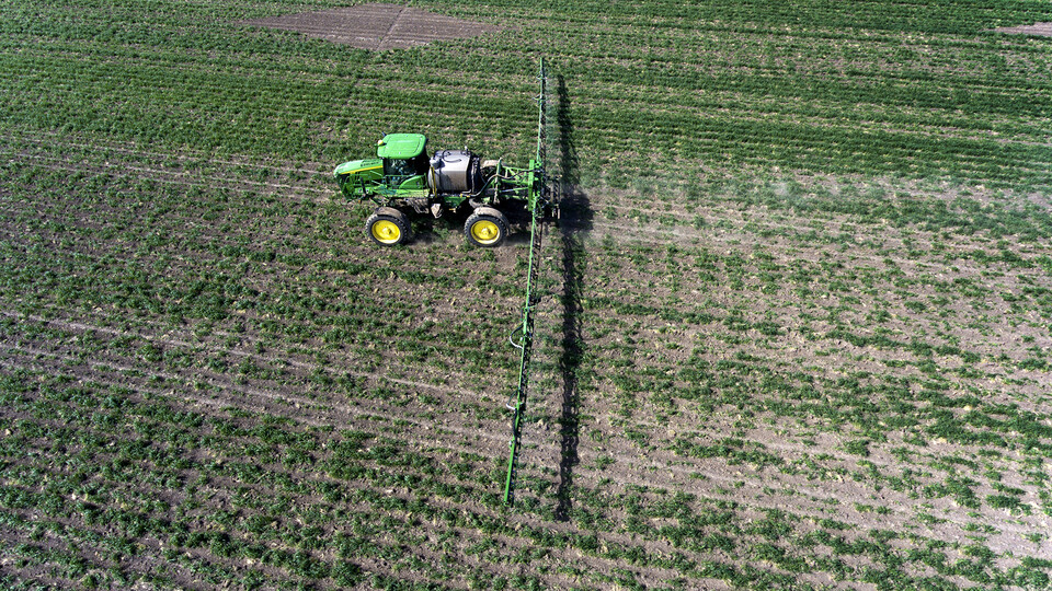 A sprayer driving across a cover crop field