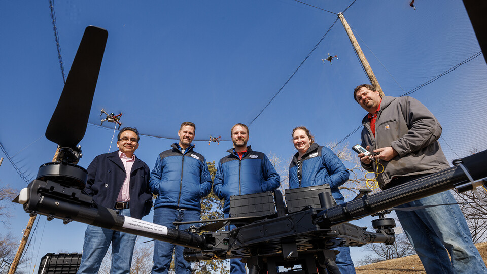 (From left) Francisco Muñoz-Arriola, Justin Bradley, Carrick Detweiler, Brittany Duncan and Trenton Franz pose among unmanned aerial vehicles at the NIMBUS outdoor flying area on Nebraska Innovation Campus.